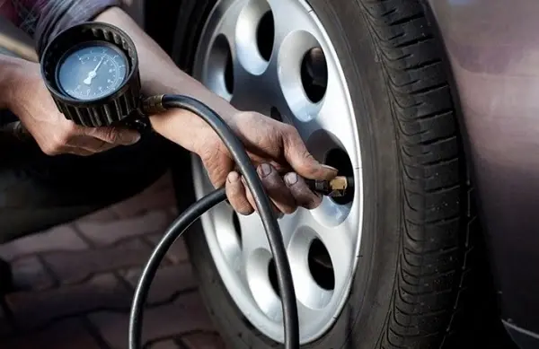 Tài xế kiểm tra ấp suất lốp trước khi lái xe trên cao tốc vào ban đêm
